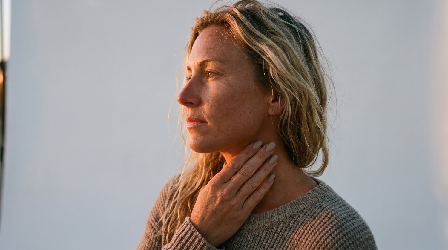 A woman resting two fingers on the side of her neck, just below the jaw, to find her pulse